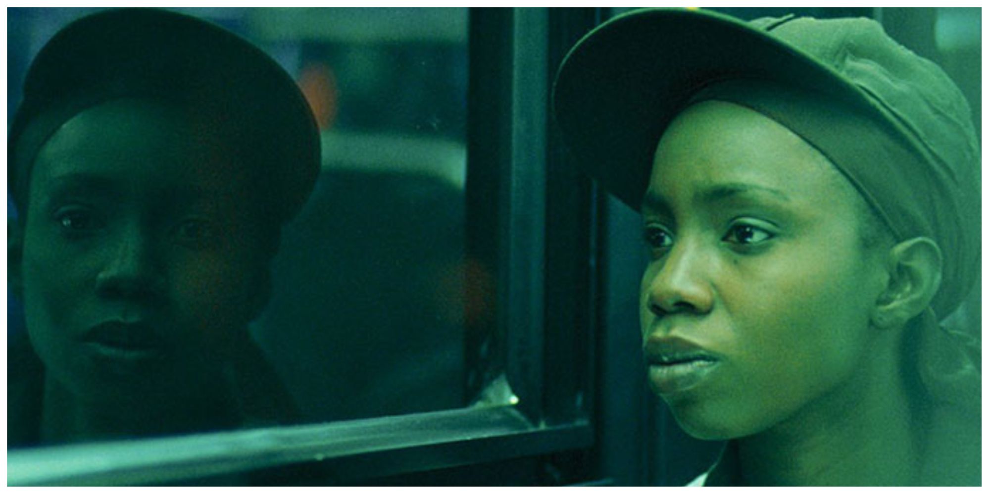 Alike in Pariah sat on the bus looking out of her window. Her reflection is looking straight at the camera.