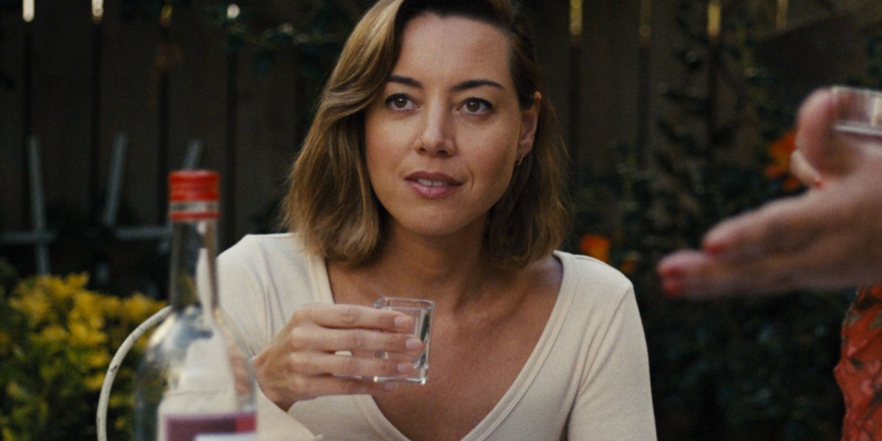 Aubrey Plaza as Emily holding up a shot glass in Emily The Criminal