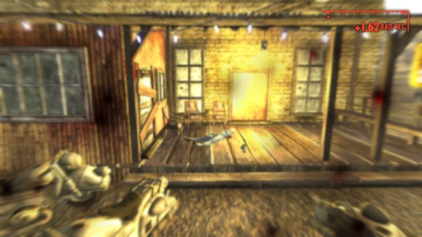 A blurry image from Fallout: New Vegas showing a dead character in front of a building.