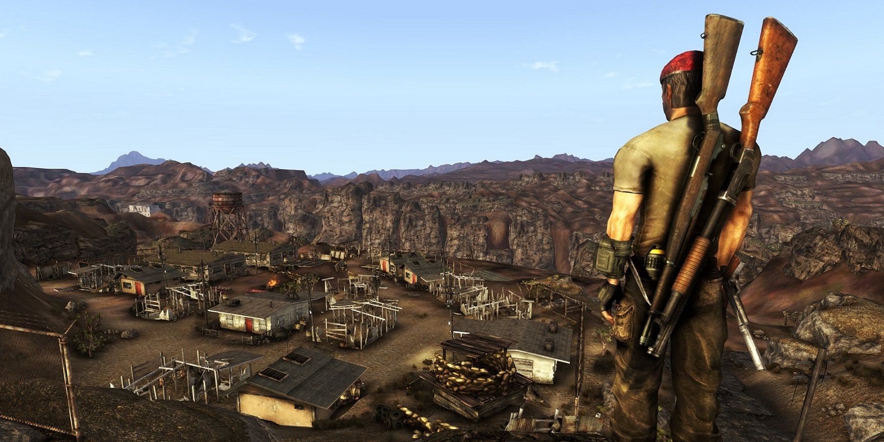 Image de Falllout: New Vegas montrant un personnage lourdement armé regardant une colonie à distance.