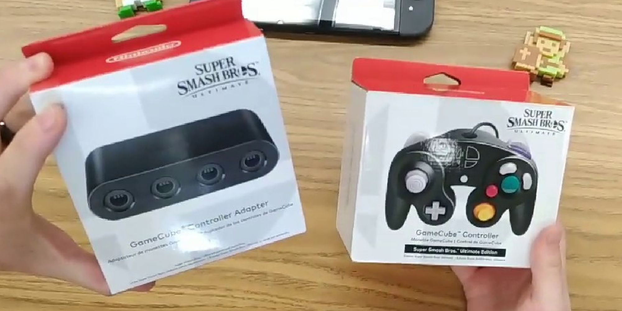 A vlogger holding a boxed GameCube controller adapter and controller for Switch