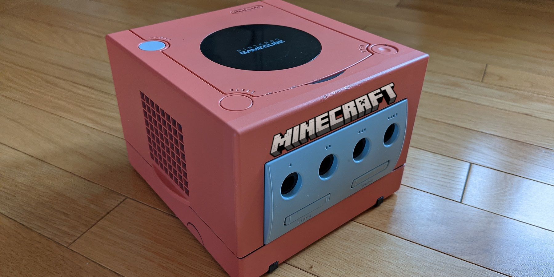 Photo of a salmon-colored Nintendo GameCube with the Minecraft logo on the front.