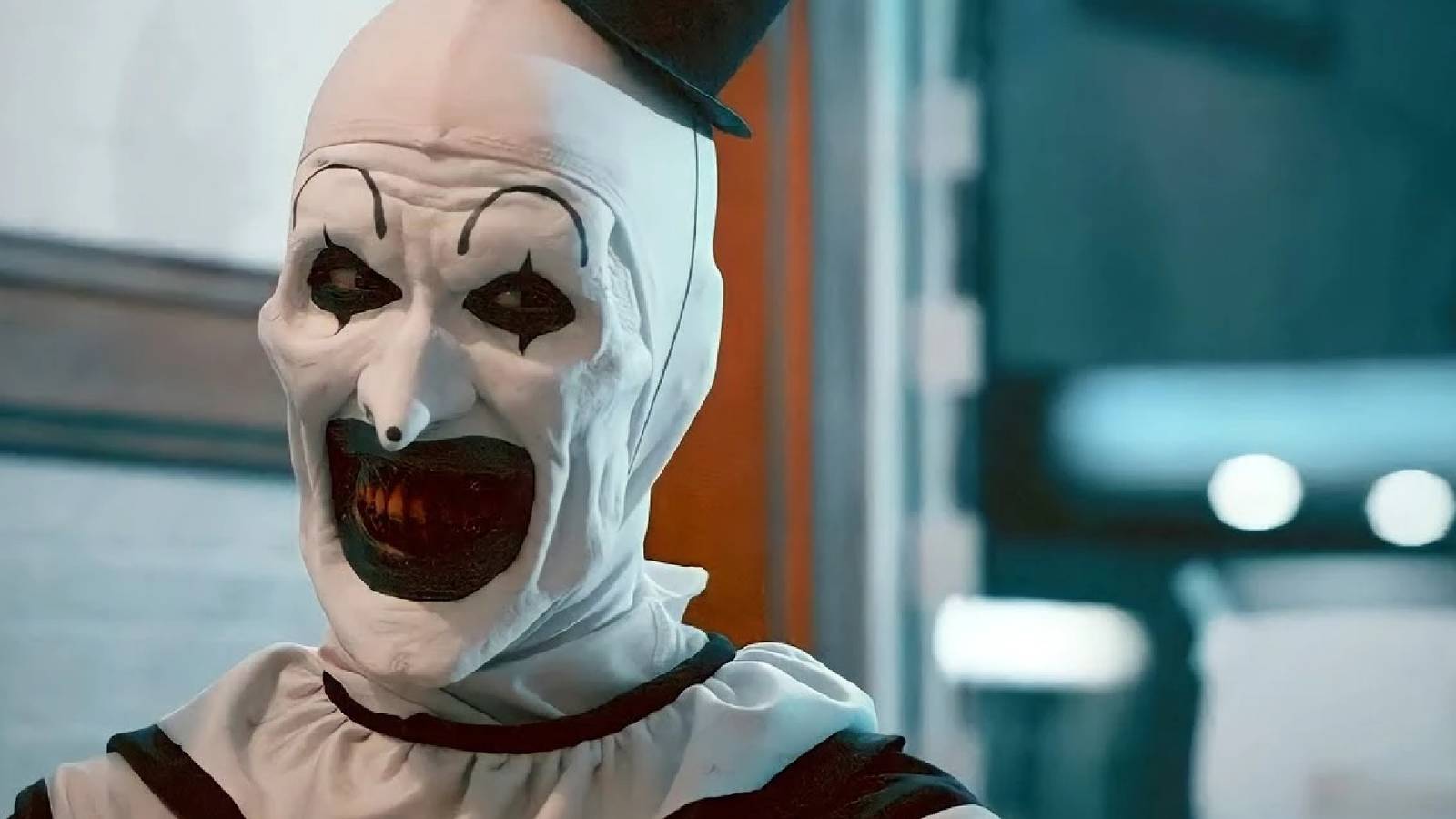 Close-up of Art the Clown in his iconic black and white clown get-up, wearing an unsettling smile on his face.