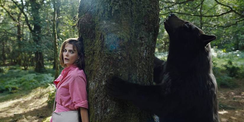 Keri Russel in Cocaine Bear hiding behind tree