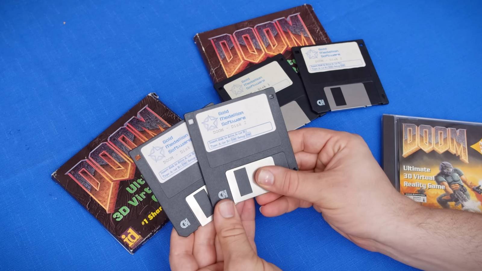 Image showing someone holding numerous disk copies of original Doom on a blue background.