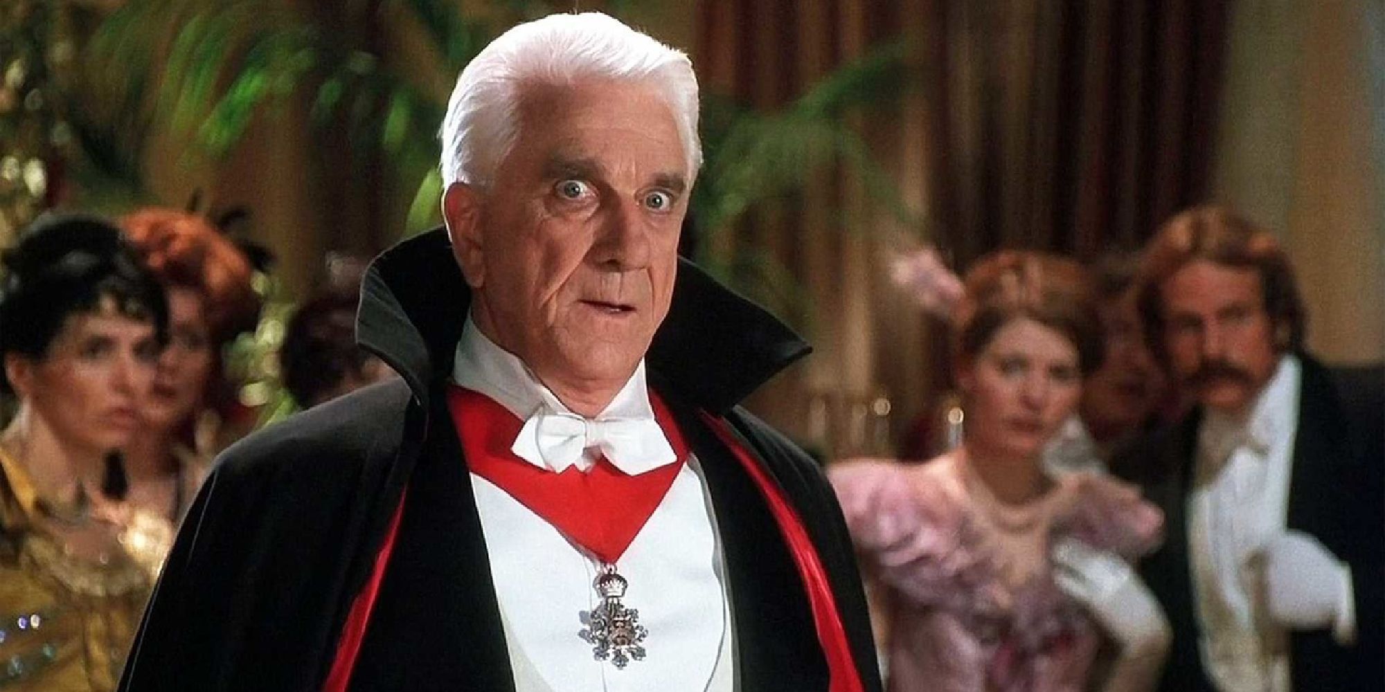 Dracula standing in a ballroom full of people with a look of shock.