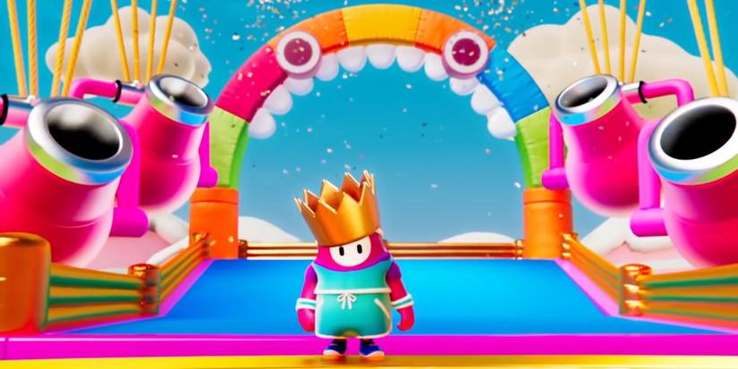 A bean person celebrates winning with a crown on their head with confetti cannons and a rainbow archway in the background.