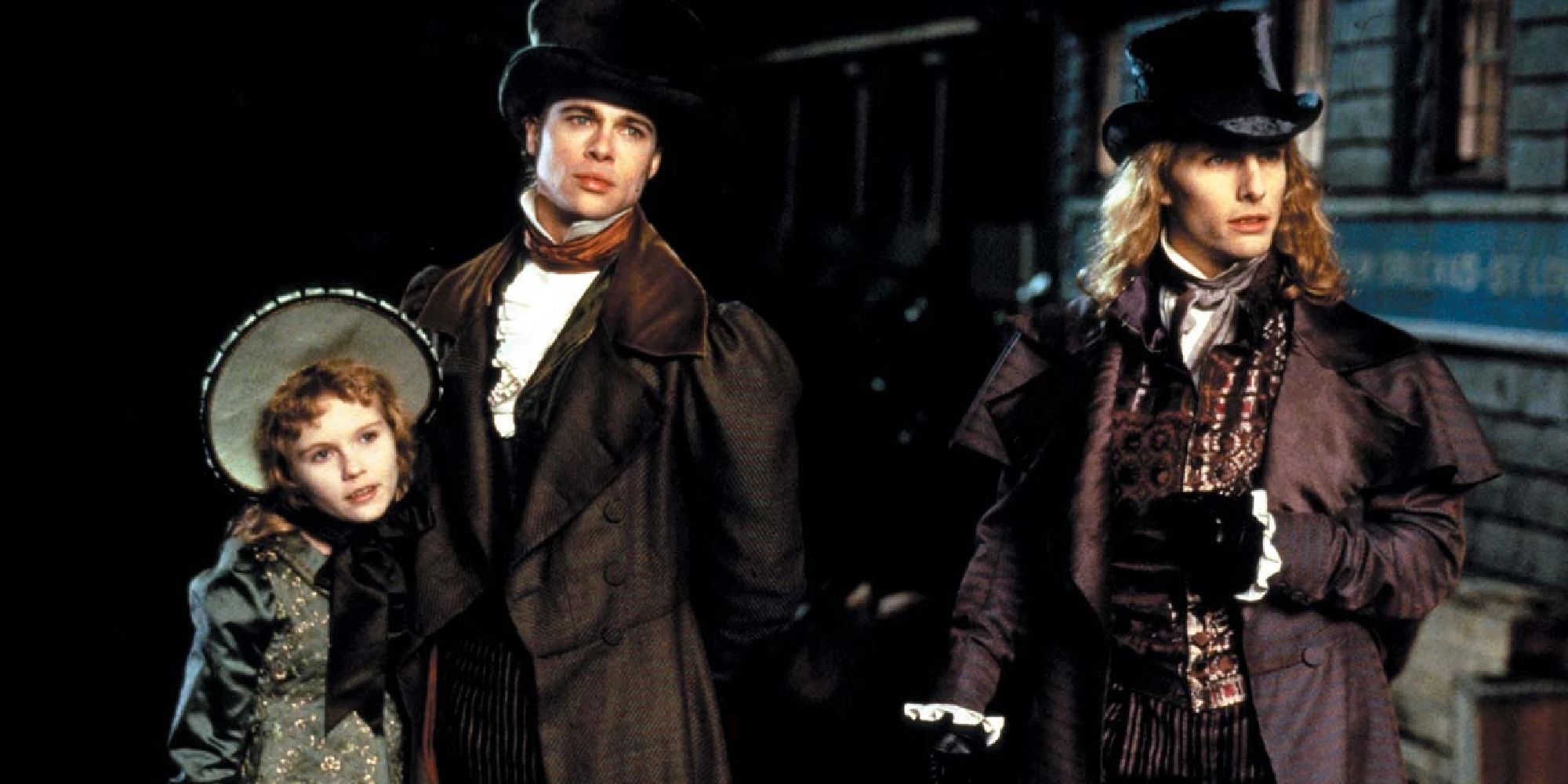 The three main characters, Lestat, Louis and Claudia standing on a road during the night, dressed in Regency-era finery.