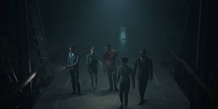 A group of people walk across a dark bridge.