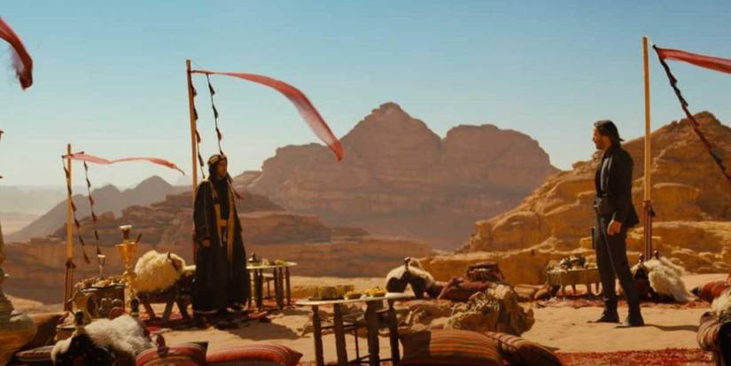 john wick standing with the elder in the desert