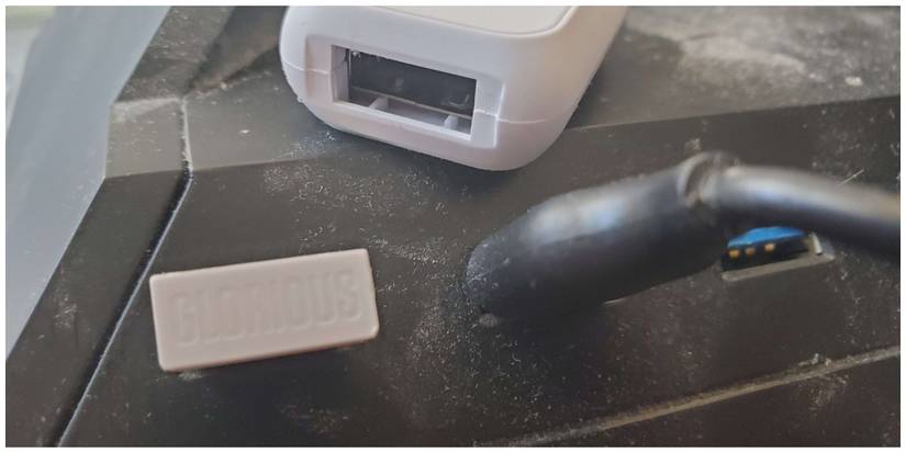 The Glorious Model O Wireless plug in dongle fits in snugly. Its protector is also pictured.