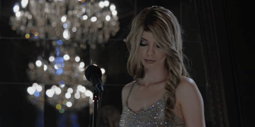 Marissa Marcel standing in front of a microphone in Immortality