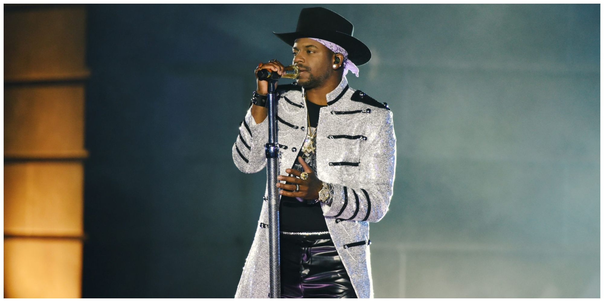 Jimmie Allen singing on stage wearing a white coat and black cowboy hat