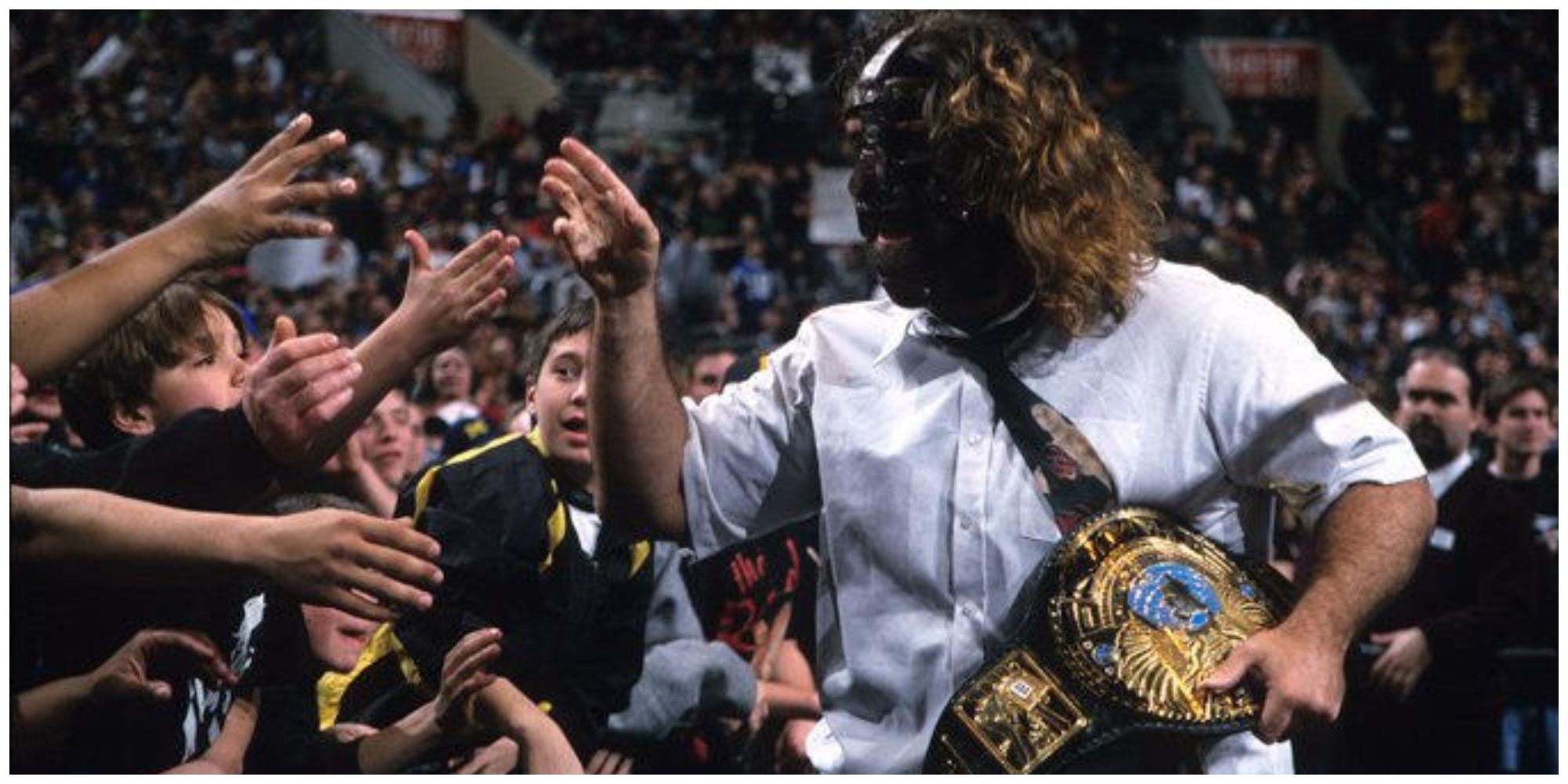 Mankind holding the WWE Championship high-fiving members of the crowd