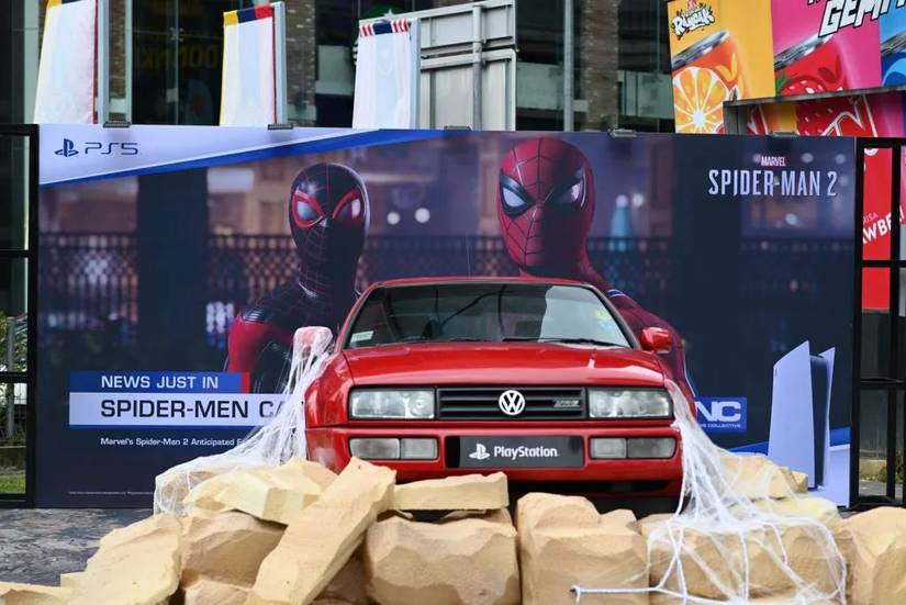 A photo of a Marvel's Spider-Man 2 PS5 ad campaign in Malaysia, showing a car covered in Spider-Man's webbing in front of a banner for Marvel's Spider-Man 2.