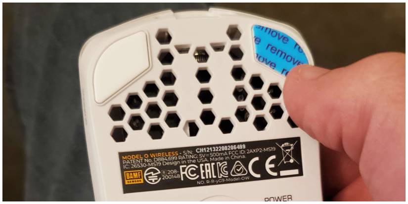 A man removing the feet stickers from the Glorious Model O Wireless mouse.