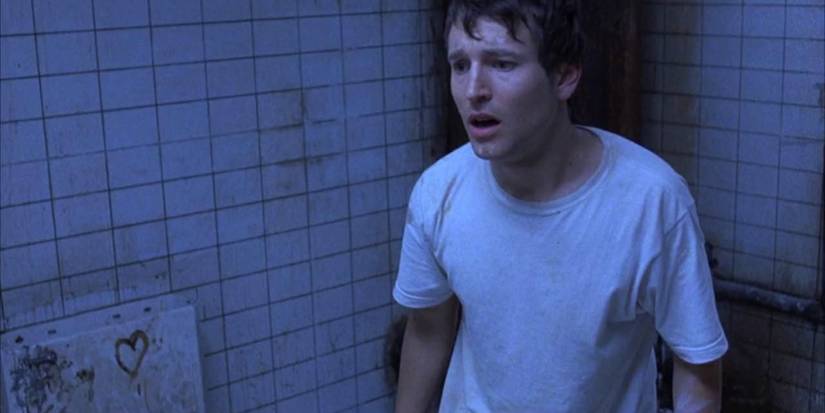 Leigh Whannell as Adam looking scared in Saw (2004)