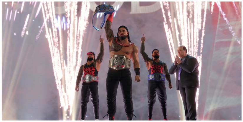 Roman Reigns holding his WWE Championship in the air, Paul Heyman facing Roman with his hands together, Jimmy Uso and Jey Uso standing behind Roman with one hand in the air. Fireworks in the background.