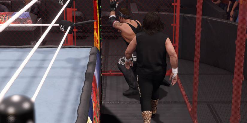 WWE2K23 Undertaker stunned on the cell wall