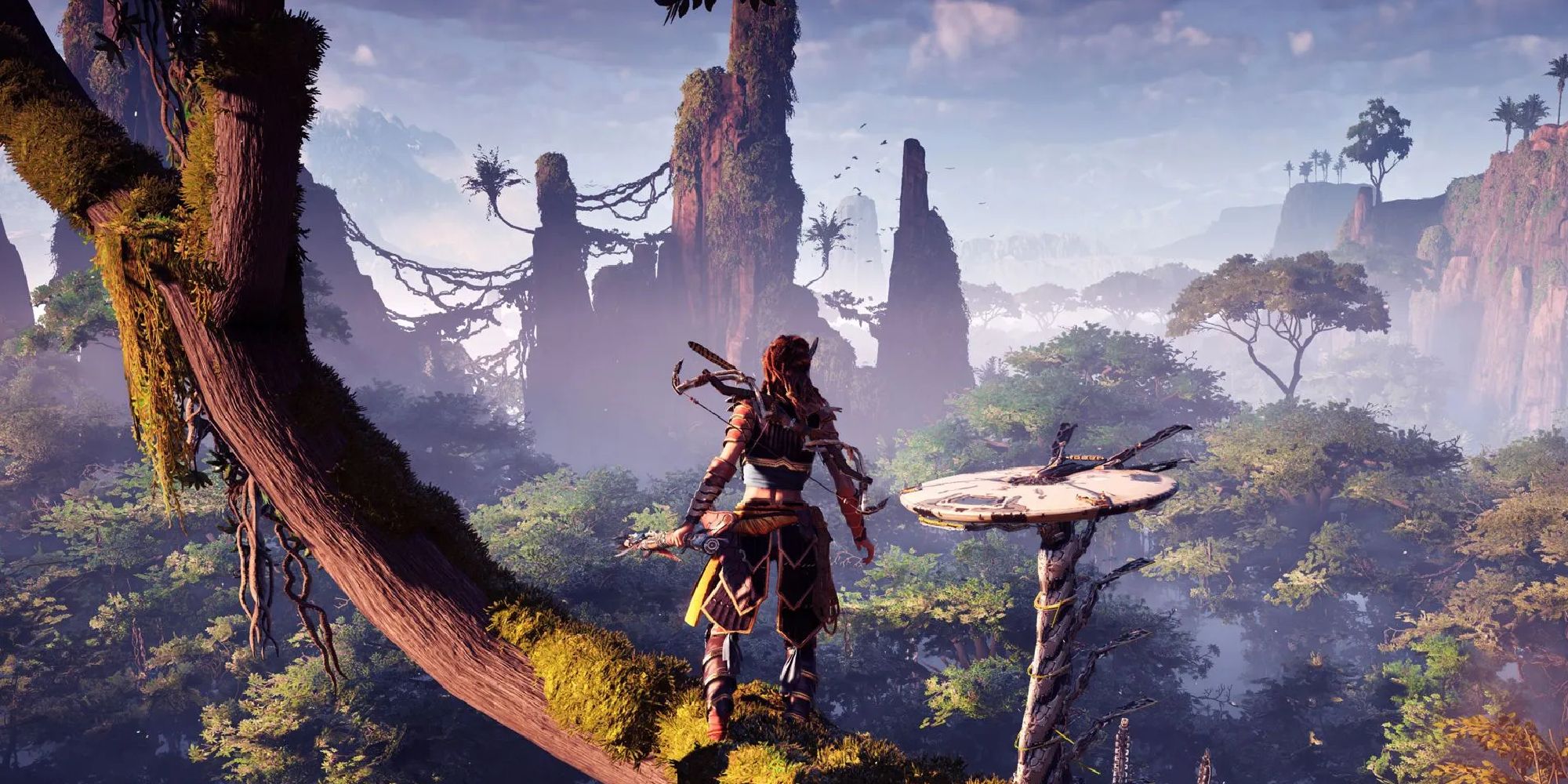 Aloy stands on a thick tree branch, overlooking the jungle-like world in Horizon Zero Dawn