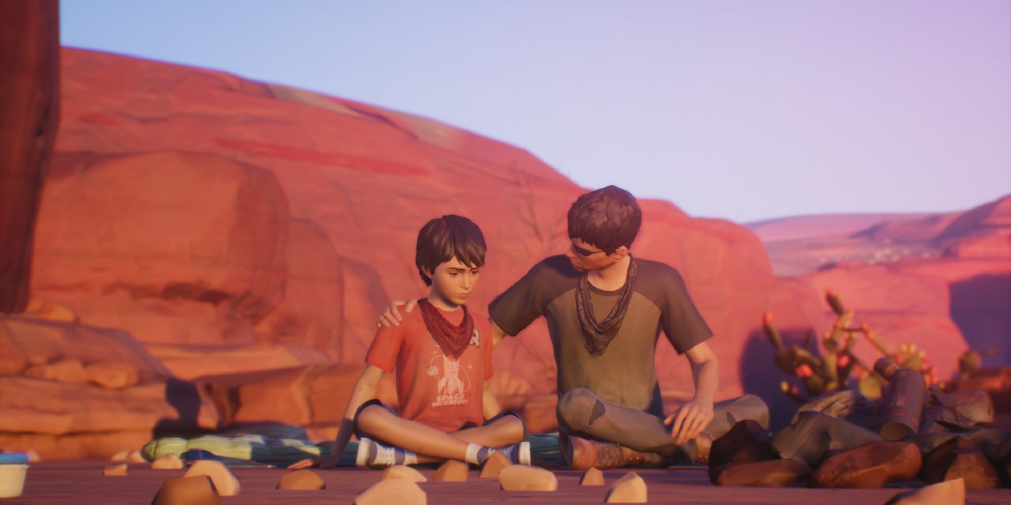 The two brothers from Life is Strange 2 sitting side by side on the ground, the older brother comforting his younger. 