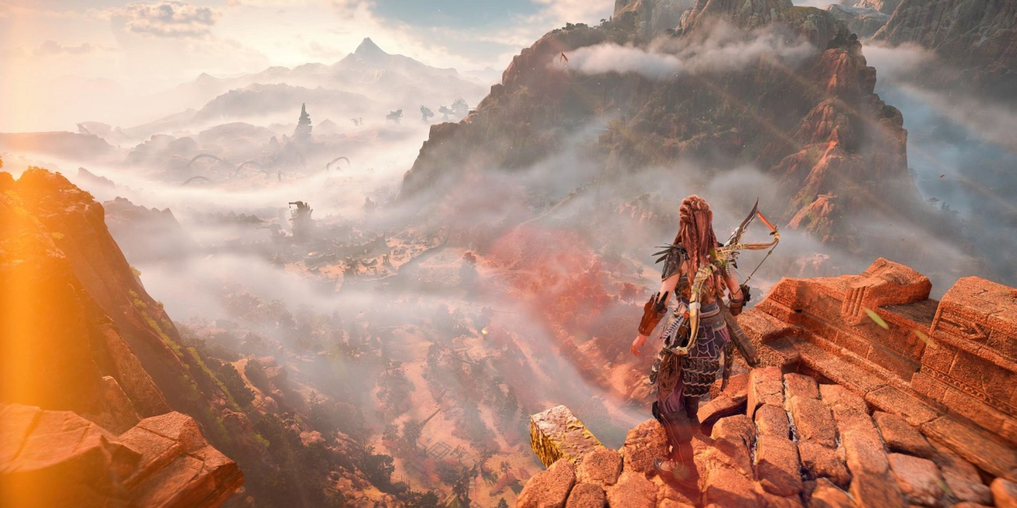 A screenshot from Horizon: Forbidden West shows Aloy at the top of a cliff overlooking the misty valley below
