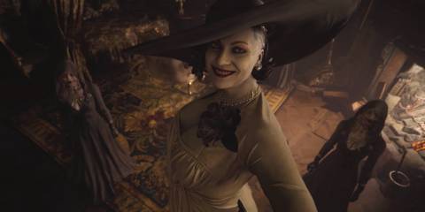 Lady Dimitrescu looking up at the captive Ethan with a wide grin. Two of her daughters can be seen in the background.