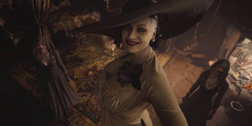 Lady Dimitrescu looking up at the captive Ethan with a wide grin. Two of her daughters can be seen in the background.