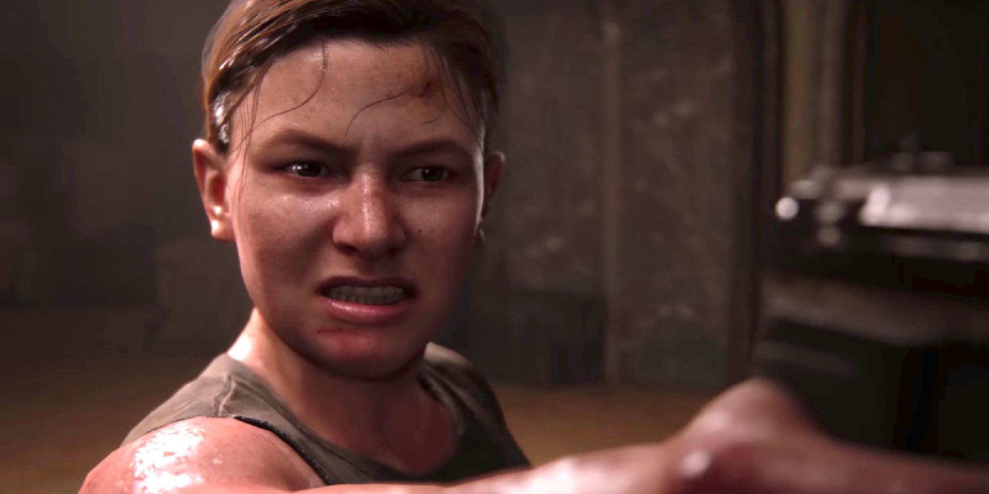 Abby from The Last of Us holding a gun with a grimace on her face.