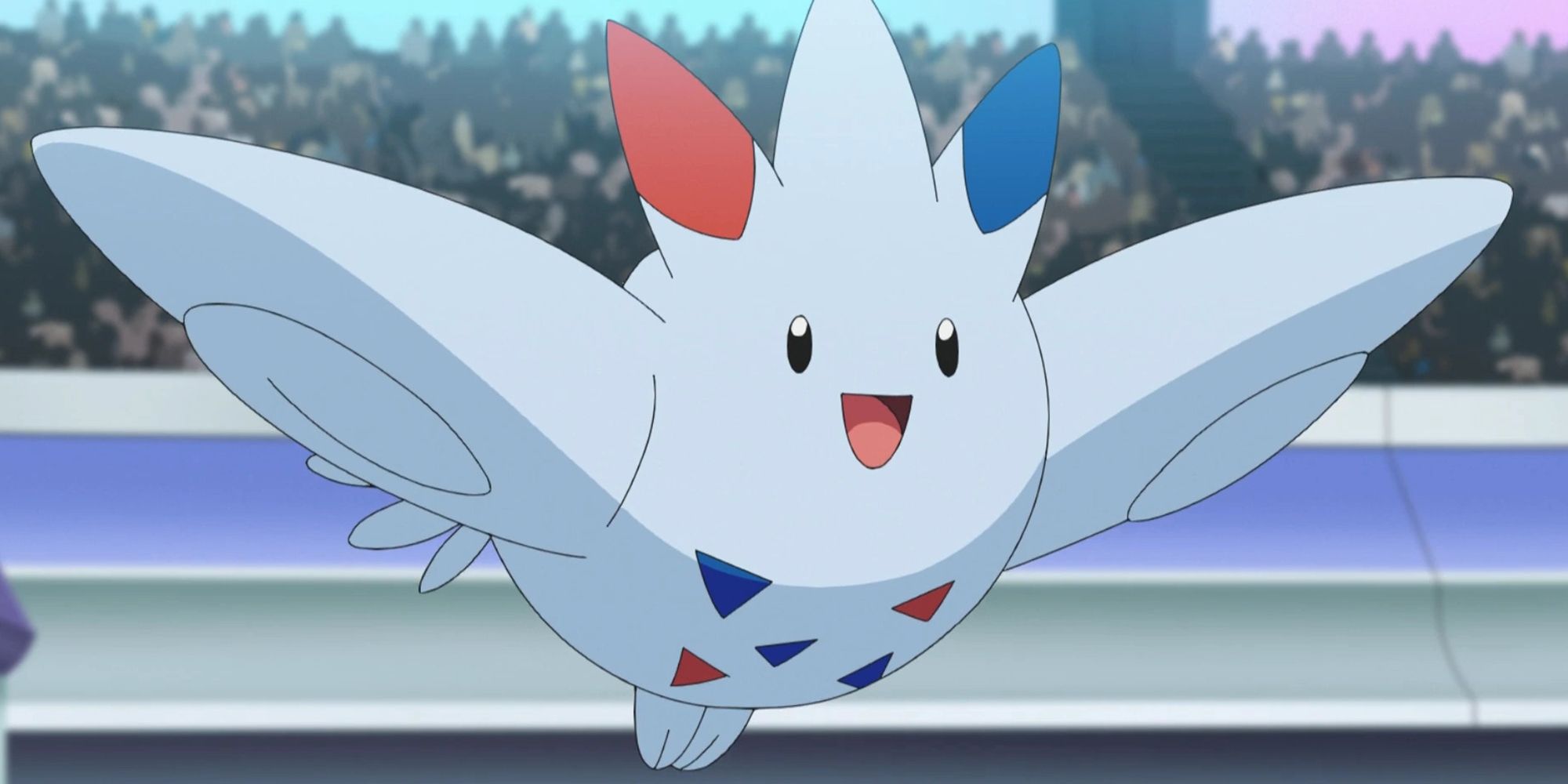 Togekiss hovers in the air with a happy look on its face