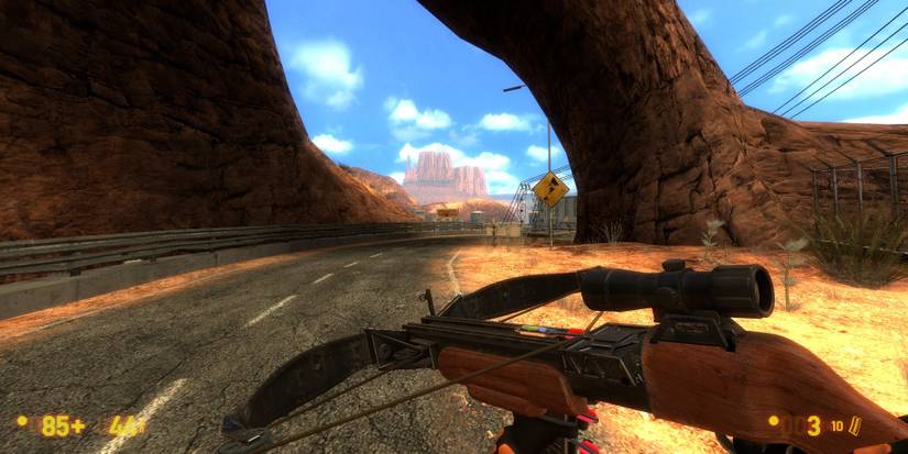 A crossbow held while the player walks under a rocky formation on a road