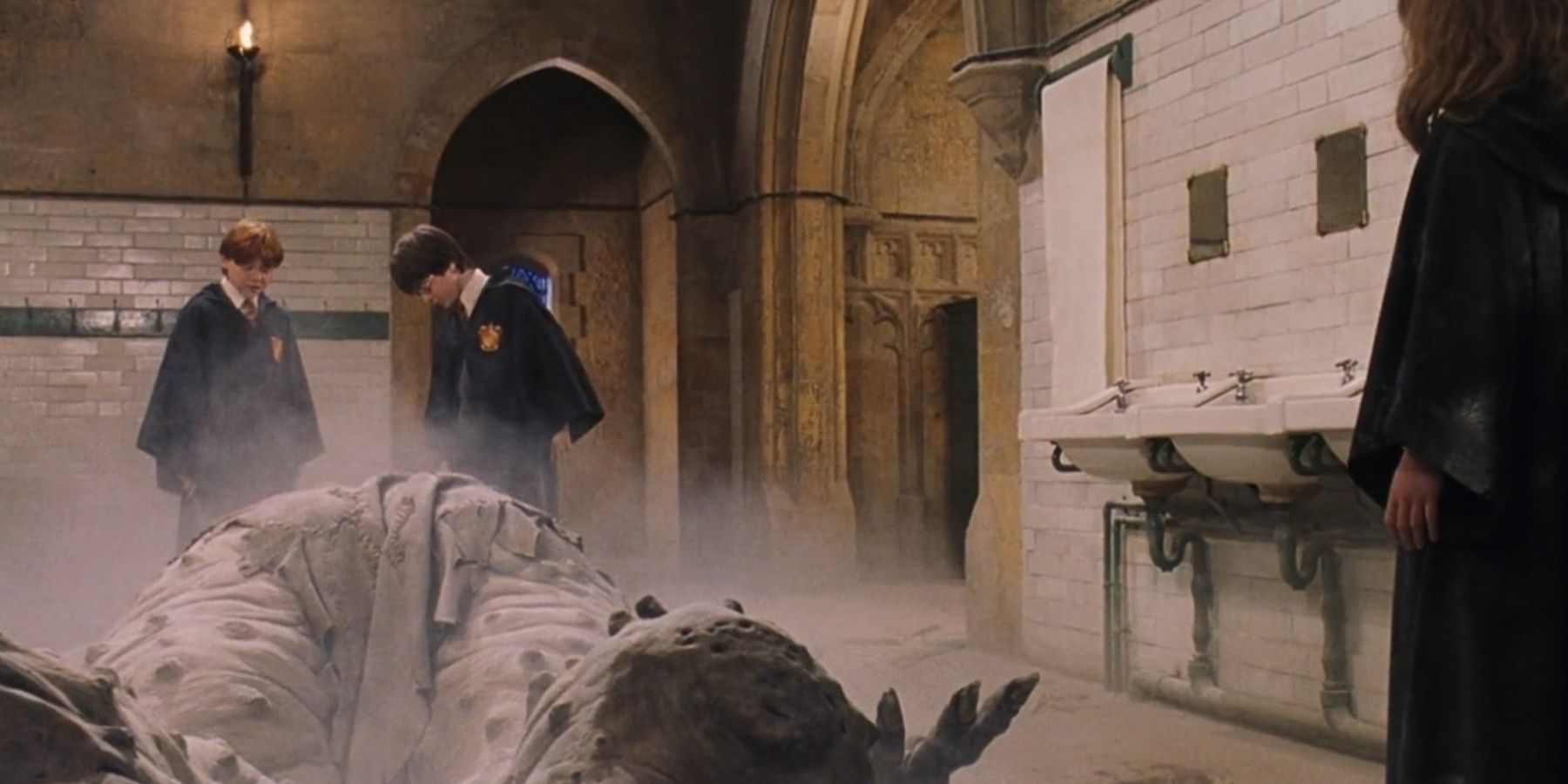 Harry, Ron and Hermione stand around the troll in Harry Potter and the Philosopher's Stone.