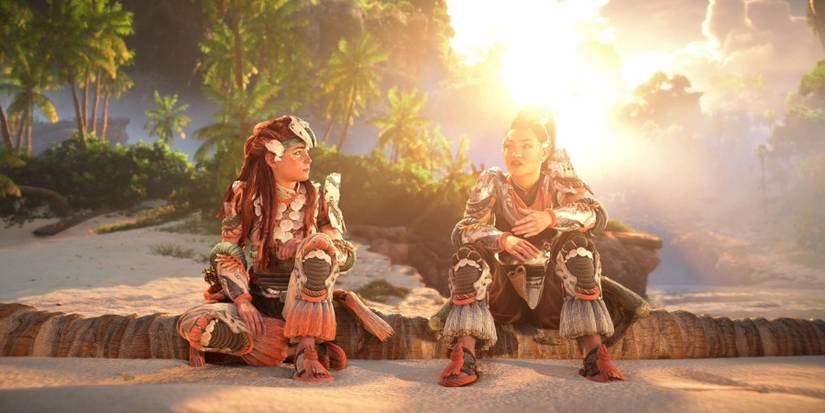 A screenshot of Aloy and Seyka sitting together and talking by the coast in Horizon Forbidden West: Burning Shores.
