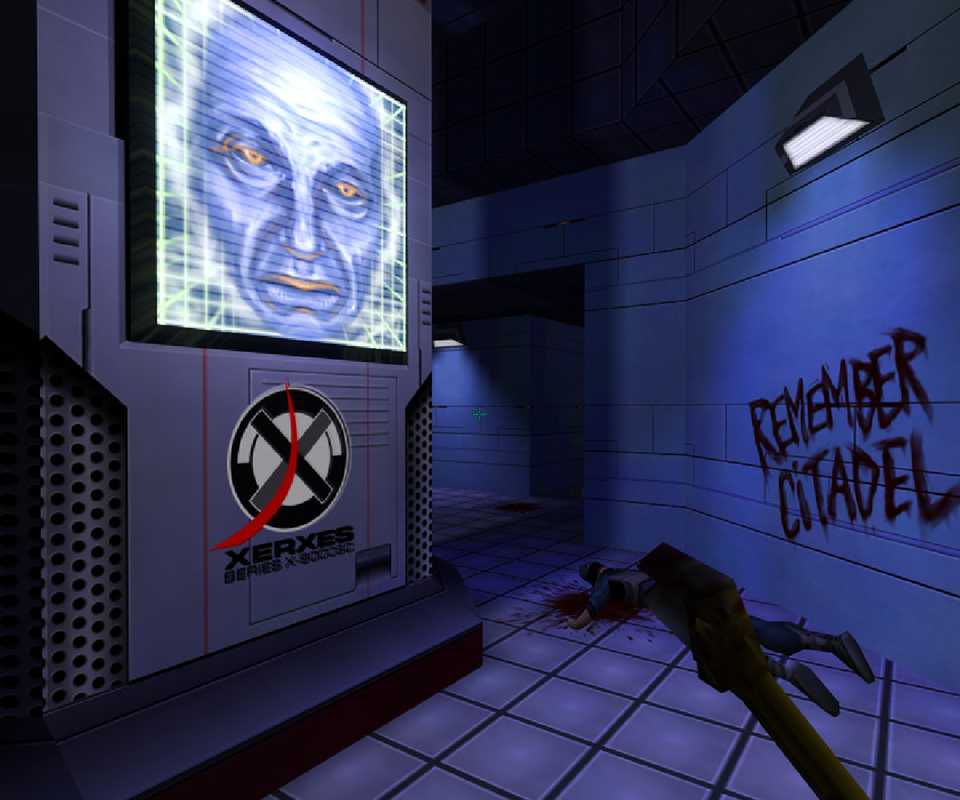 A screenshot showing the desolate hallways of System Shock 2, a screen showing an AI face on one wall, graffiti on the other and a dead body.