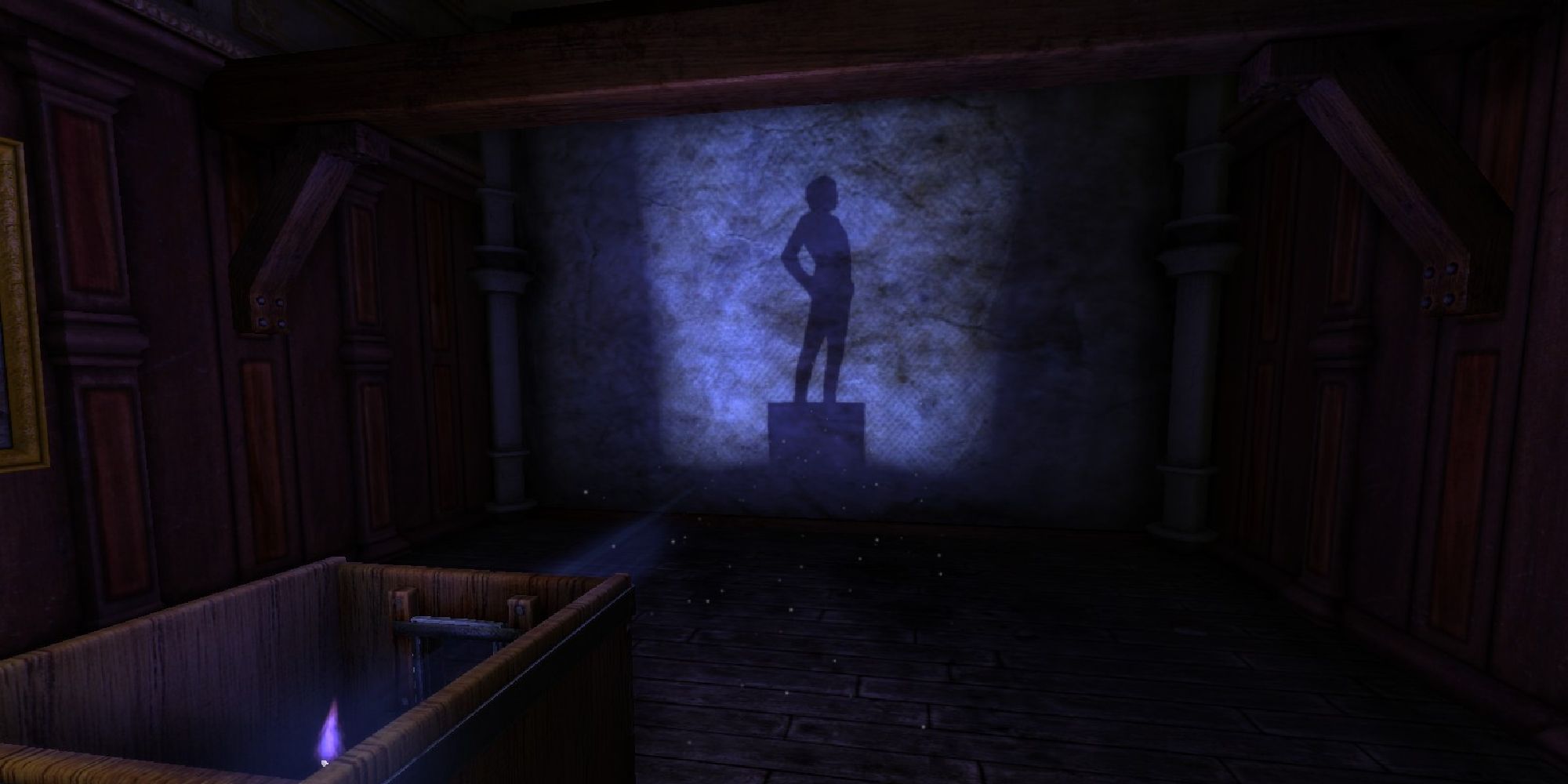 A dark room showing the outline of a statue on the far wall, cast in a blue light.
