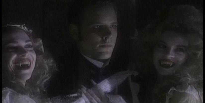 Johnathan standing in the midst of two vampiric women who are both laughing. 