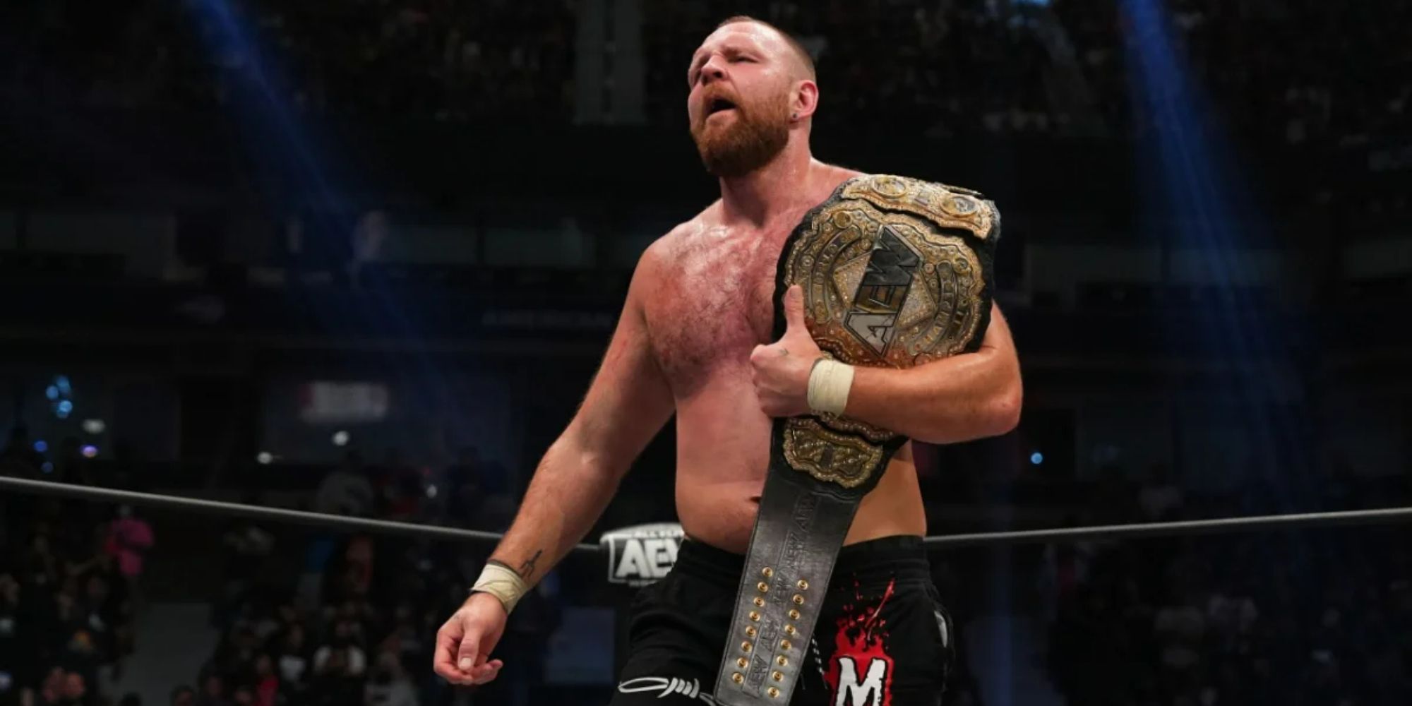 Former WWE and current AEW star Jon Moxley in the ring with the AEW World Championship belt on his shoulder.