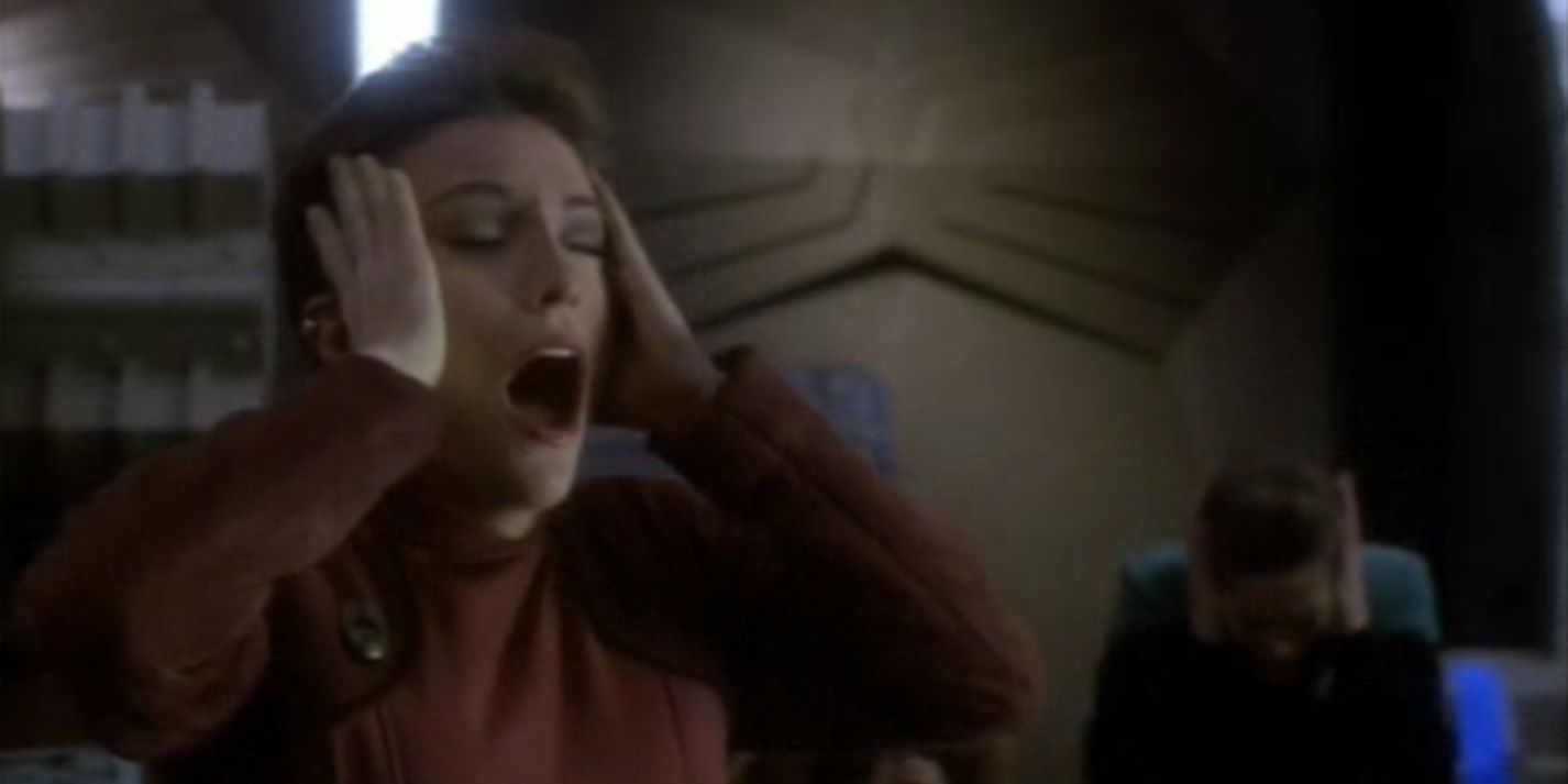 A woman clutches her head as she is freed from a telepathic alien influence.