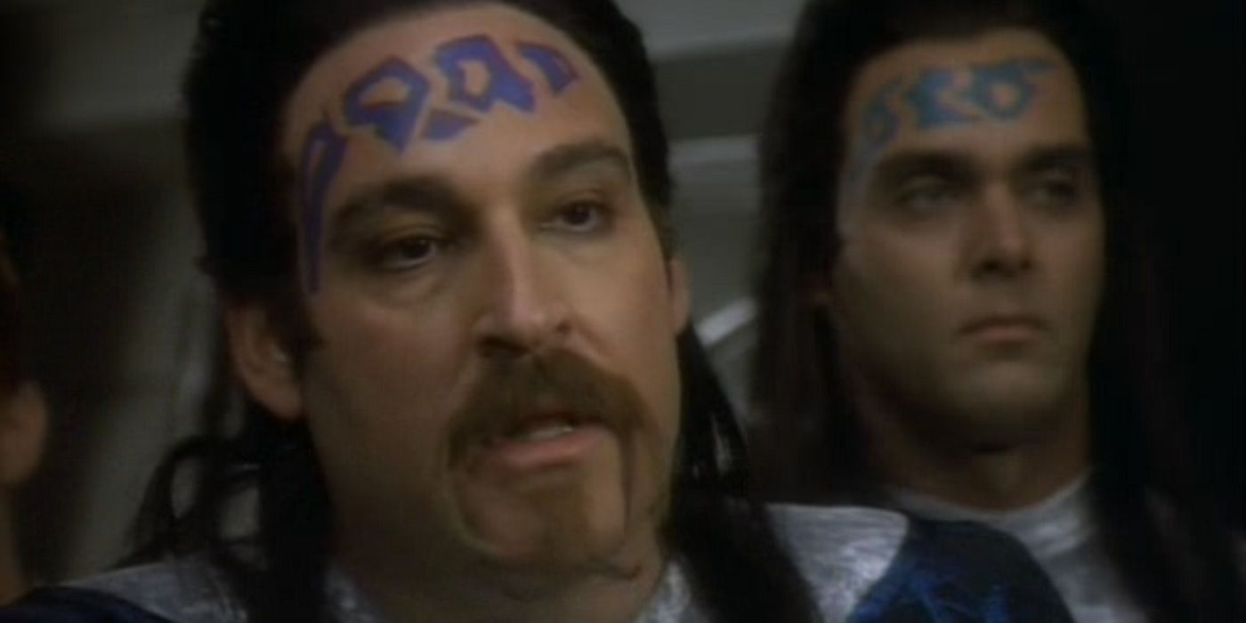 Two male, humanoid aliens with blue geometric tattoos on their foreheads.