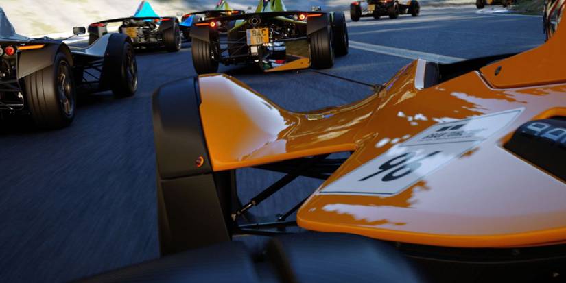 close up of orange racing car with other cars in front of it