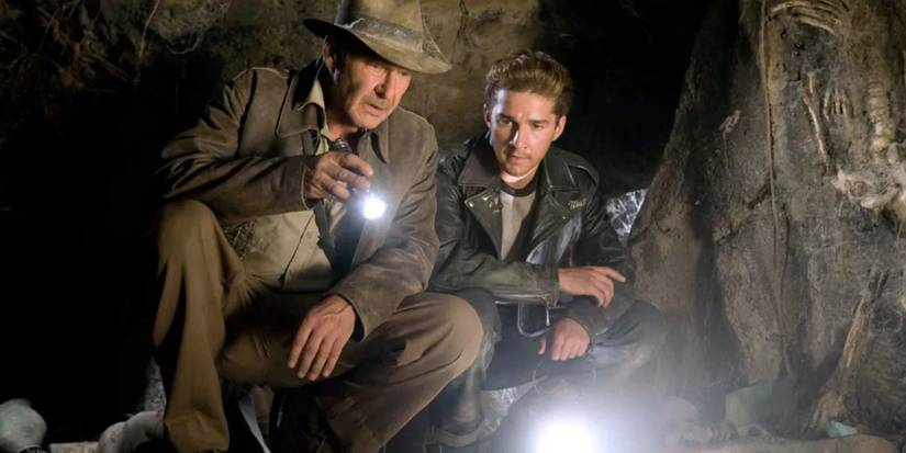 indiana jones crouching in a cave with mutt