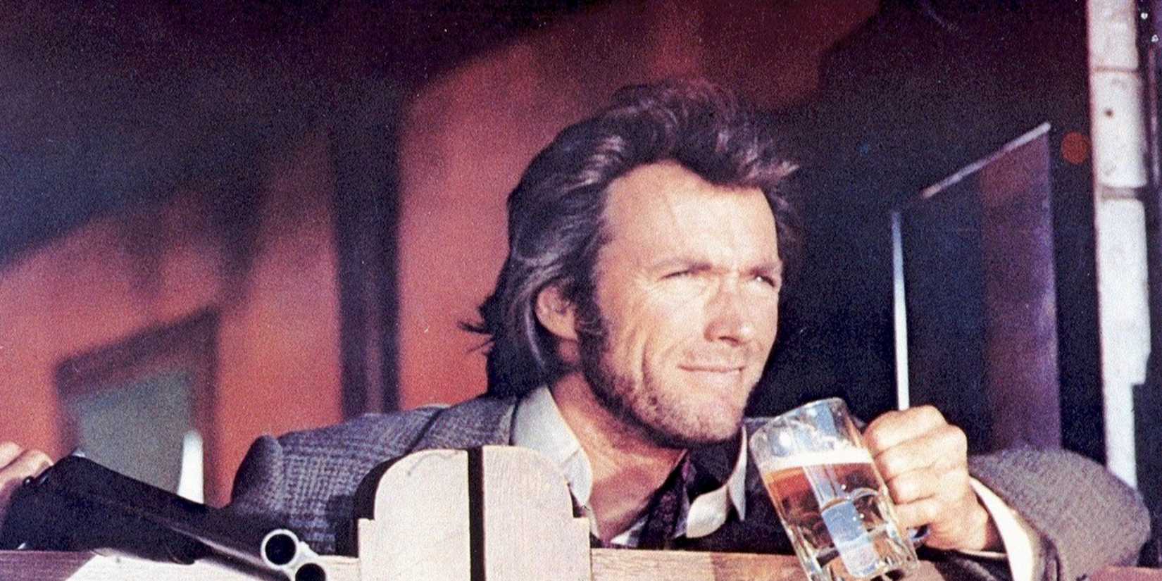 Joe Kidd drinking a beer with a shotgun next to him