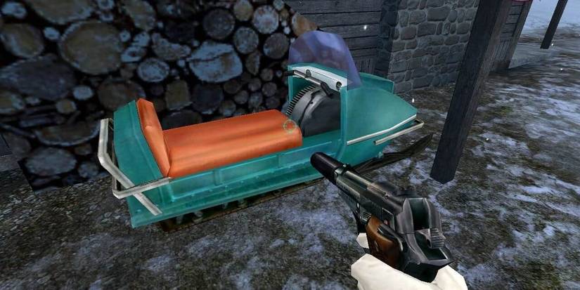 Player character holding a pistol looking at a parked snowmobile next to a pile of logs