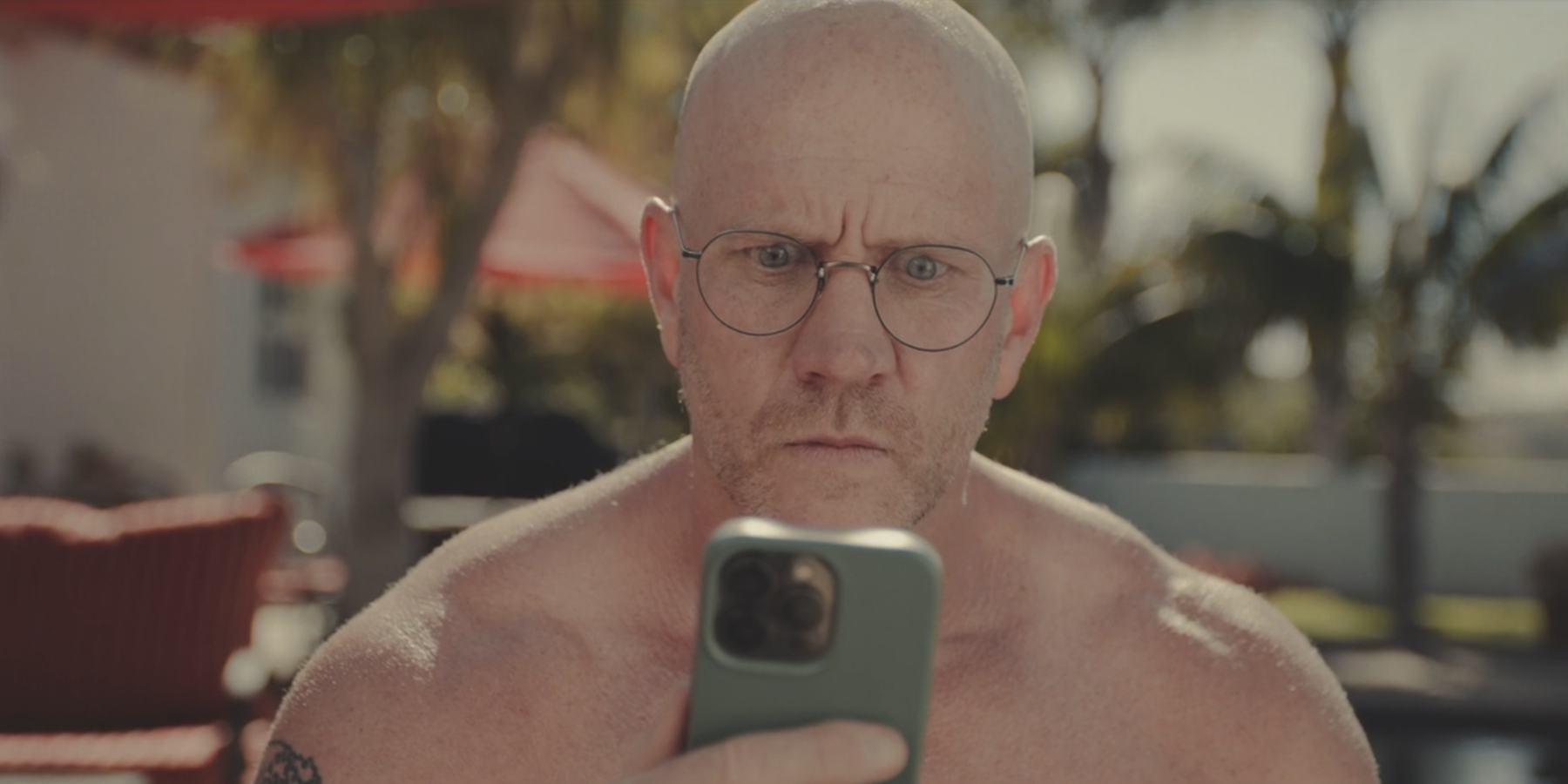 bald man with glasses in Welcome to Wrexham looking at phone