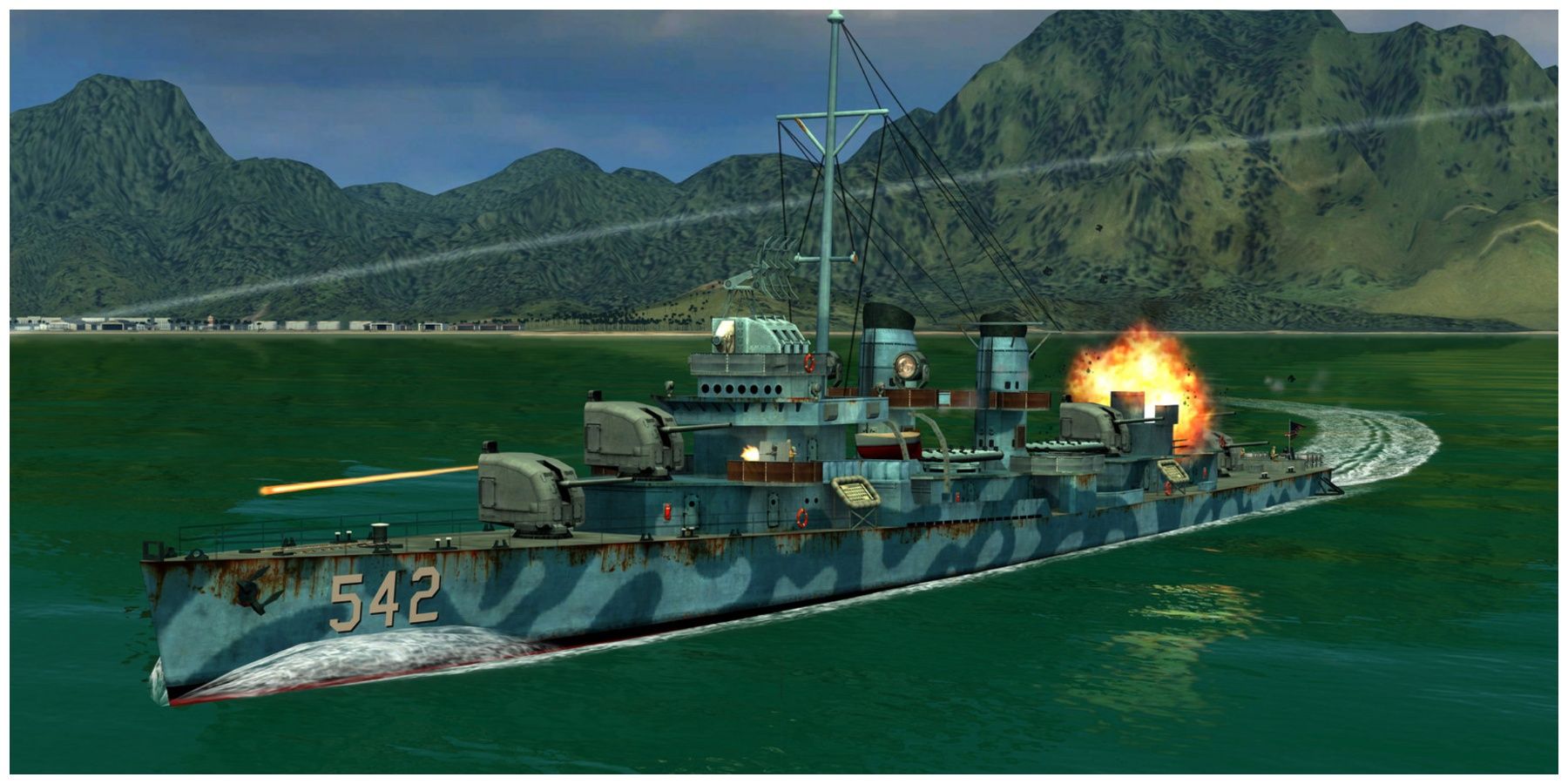 A blue camoflauged warship sailing away from some mountains whereas firing shots