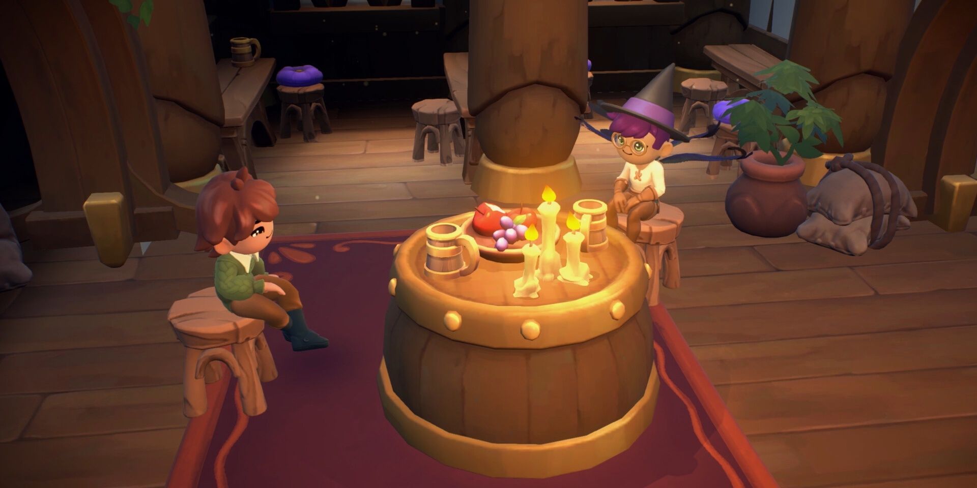 Two individuals, one of which is in a witch's hat, sitting on stools on either side of a barrel table with candles, mugs, and a fruit platter on it in Fae Farm