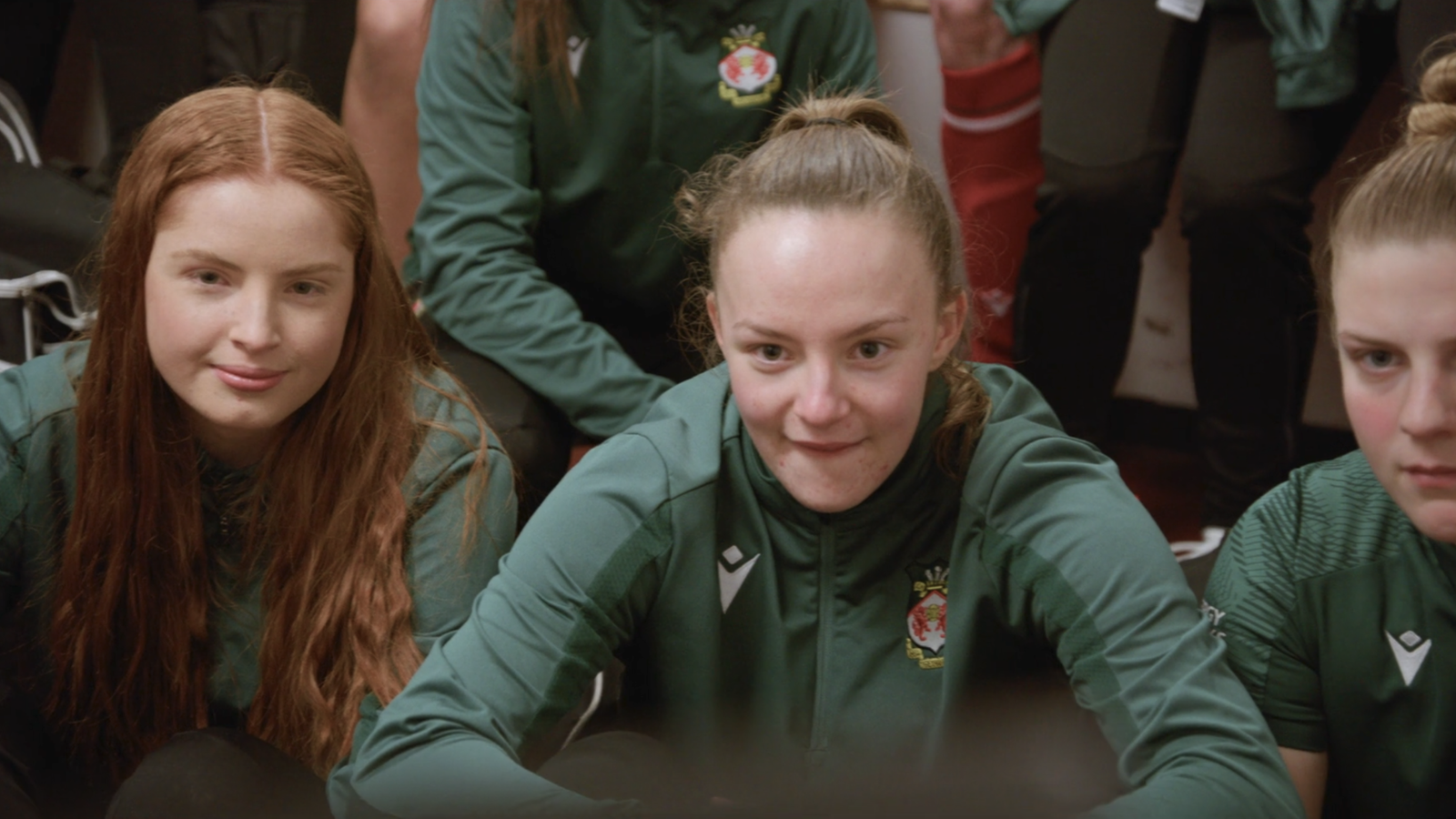 Wrexham women's team watching screen in locker room