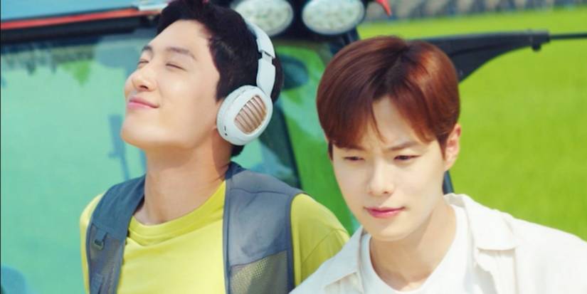 two men sit with each other, one listens to music