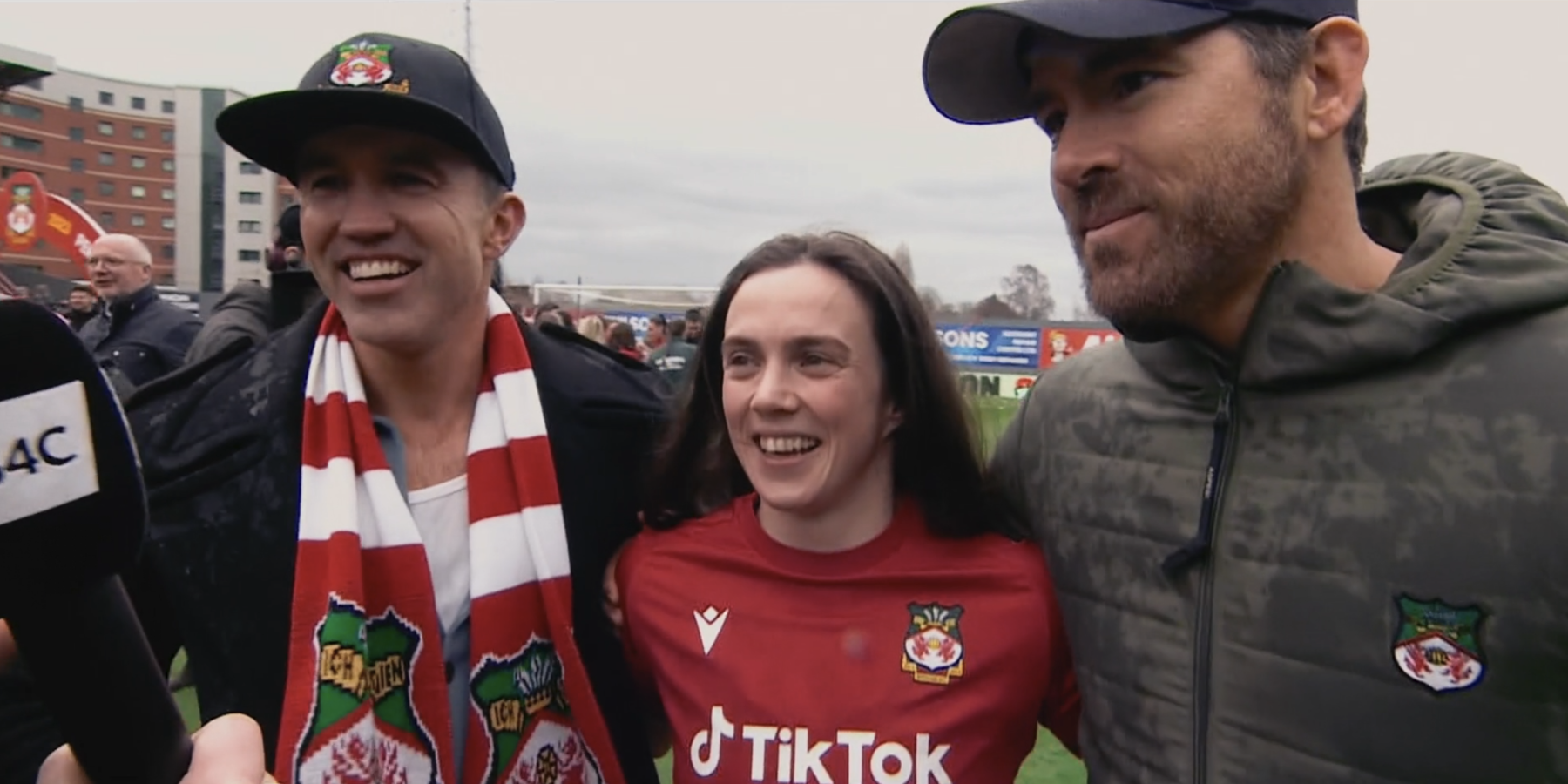 Rob McElhenney and Ryan Reynolds posing with Wrexham women's striker Rosie Hughes.