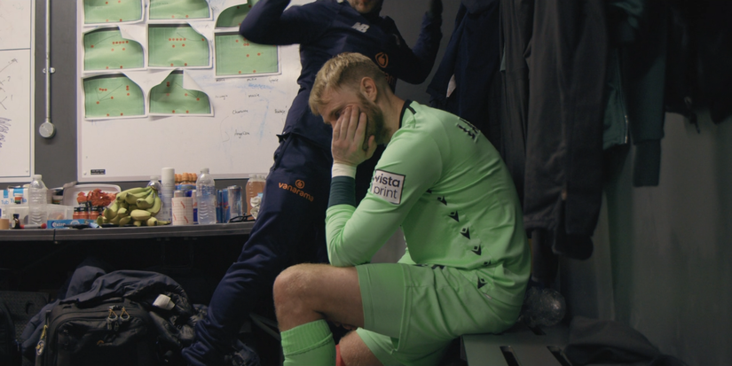 Wrexham goalkeeper Rob Lainton sad in locker room.